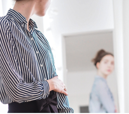 woman looking at outfit, woman looking at her outfit, black and white striped blouse, black and white striped top, button down shirt, women's button down, woman looking in mirror